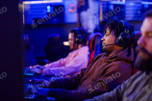 Preview: Side view of multicultural gamer with headset playing video games.