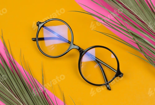 Preview: Stylish round glasses on a colored background with palm leaves