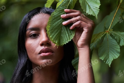 Preview: black woman covering eye with green leaf
