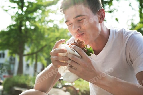 Preview: Young man eating hamburger
