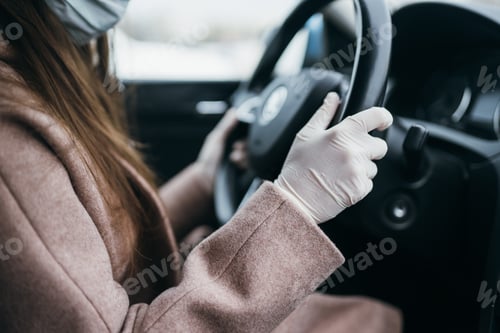 Preview: Young woman in a mask and gloves driving a car