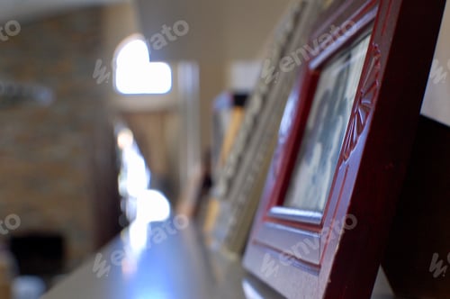Preview: Frames with family photos in them on a long white shelf in house