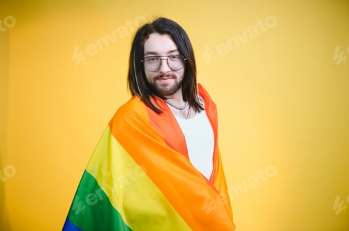 Preview: Gay man hold rainbow striped flag isolated on colored background studio portrait.