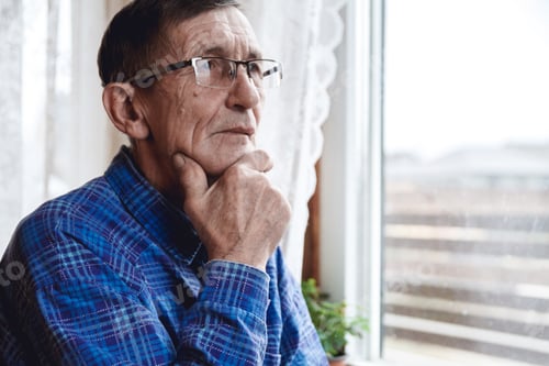Preview: Senior standing at the window and thinking about something or fo