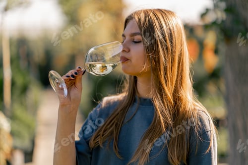 Preview: A girl takes a sip of wine from a glass and holds it out to the camera with smile