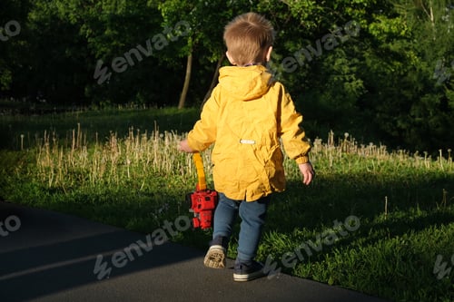 Preview: Toddler boy with toy car walking outdoors in spring.