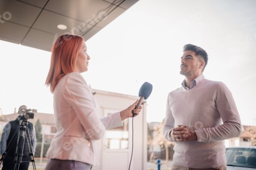 Preview: Journalist interviewing businessman holding microphone outdoors