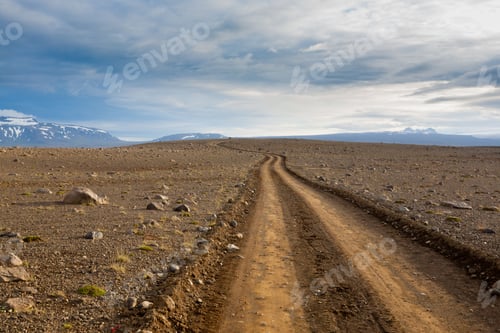 Preview: Remote dirt road winding through barren landscape with distant mountains.