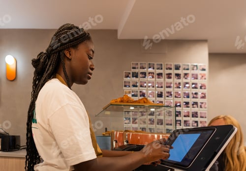 Preview: Young waitress serving customers using a touchscreen computer in a café.