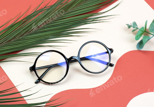 Preview: Stylish round glasses on a colored background with palm leaves