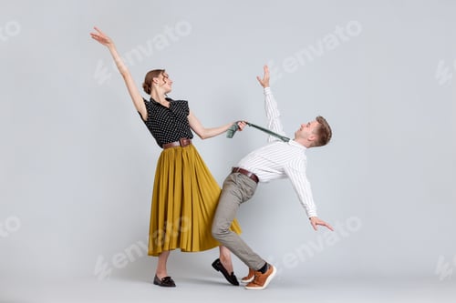 Preview: Happy couple in retro outfits dancing on light grey background