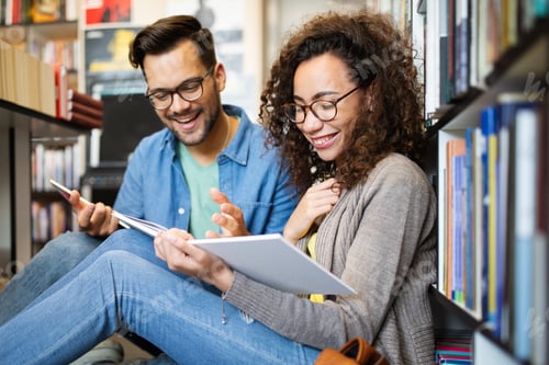 Preview: University students in cooperation at library. Group of young friends reading books