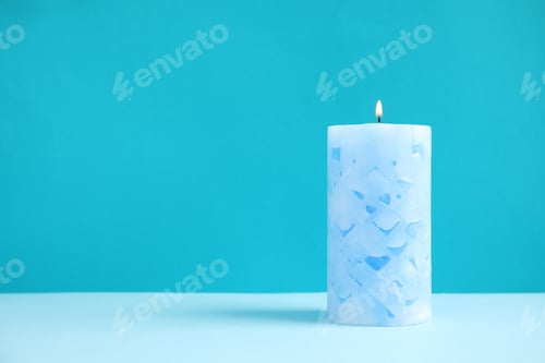 Preview: Alight wax candle on color background. Space for text