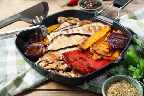 Preview: Tasty grilled vegetables and mushrooms in pan, spices and tongs on wooden table, closeup