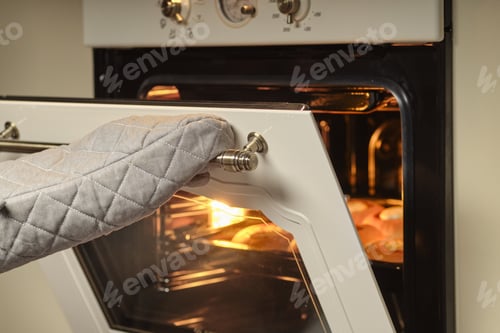 Preview: Female hands in mittens open oven door