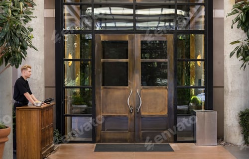 Preview: Bellhop standing at wooden reception desk of a downtown hotel.
