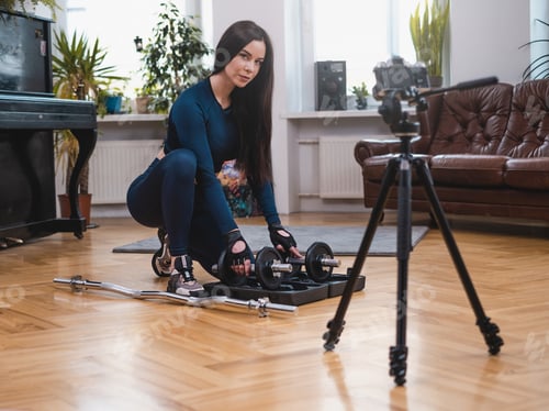 Preview: Sportswoman in apartment prepares her equipment with photocamera
