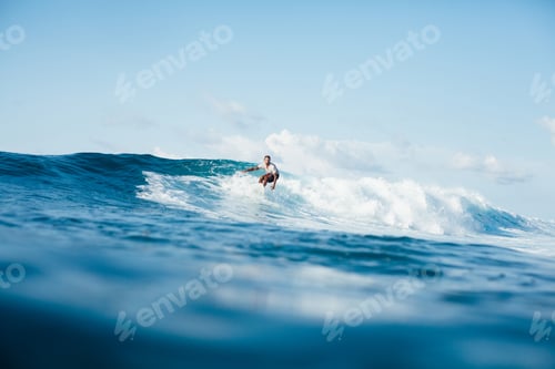 Preview: handsome athletic man surfing on ocean wave