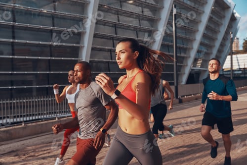Preview: Group of young people in sports clothing jogging together outdoors