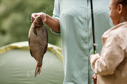 Preview: Close up of female hand holding fish outdoors during fishing trip with family