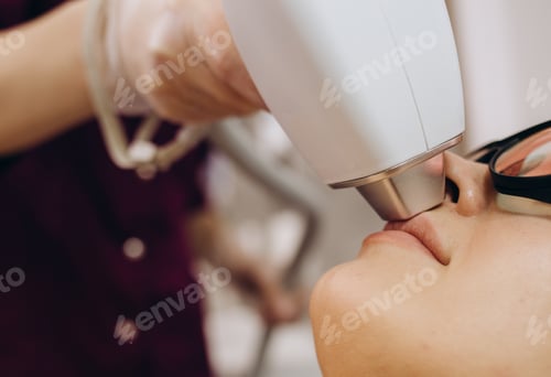 Preview: Therapist beautician makes a laser treatment to young woman's face at beauty SPA clinic.