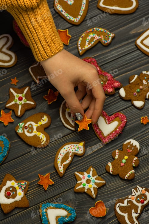 Preview: Hand Holding Star-Shaped Gingerbread Cookie on Wooden Table