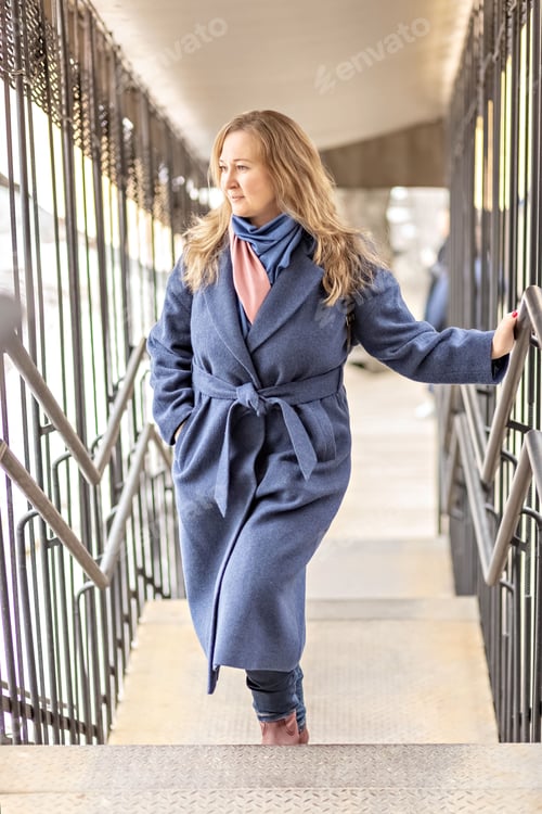Preview: Portrait of a young woman with blonde hair in a blue coat. Spring
