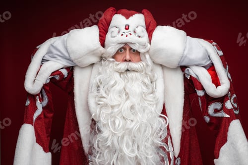 Preview: father frost in long warm coat, red mittens and a hat panics and holds his head