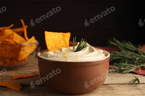 Preview: Delicious hummus with nachos and rosemary on wooden table, closeup