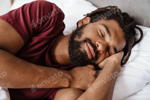 Preview: Happy african american man with dreadlocks sleeping in bed at home