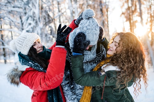 Preview: A group of cheerful young friends having fun outdoors in snow in winter forest