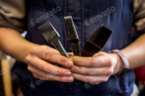 Preview: Close up of person holding three metal saddle making tools.