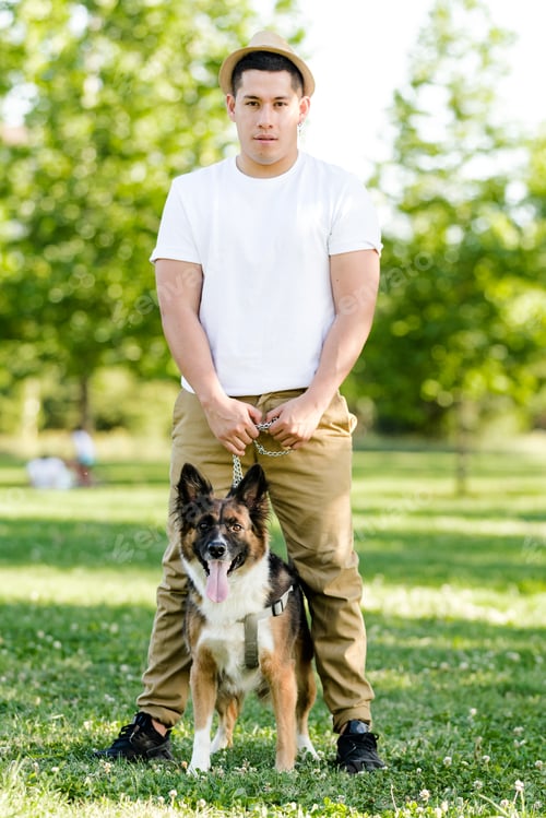 Preview: Young man walking his dog in the park. Latin model posing and watching on camera