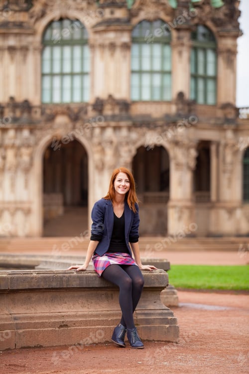 Preview: beautiful young woman sitting on the fountain near wonderful building