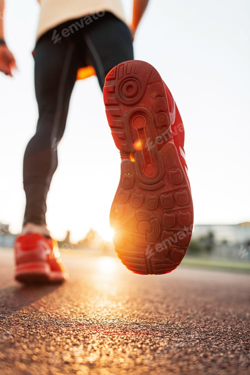 Preview: Sports man in sportswear with sneakers runs at sunset, close-up. Male legs with red shoes running