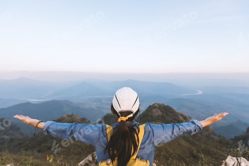 Preview: Hiker woman standing with hands up achieving the top.