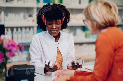 Preview: African american woman pharmacist selling drugs to a senior customer in a pharmacy