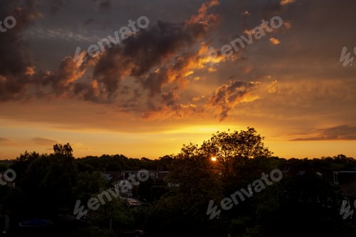 Preview: Beautiful scenery of a landscape with trees and buildings with the sunset in the background