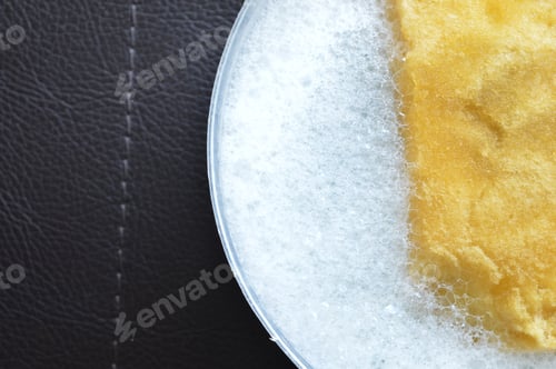 Preview: yellow sponge and liquid soap foam isolated on a black background