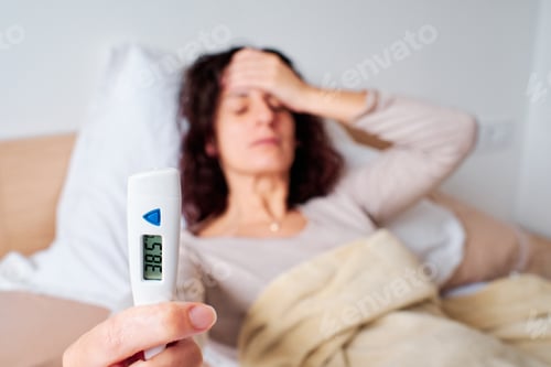 Preview: young woman using a fever thermometer