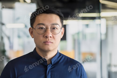 Preview: Closeup portrait of successful asian investor in glasses and blue shirt, businessman looking