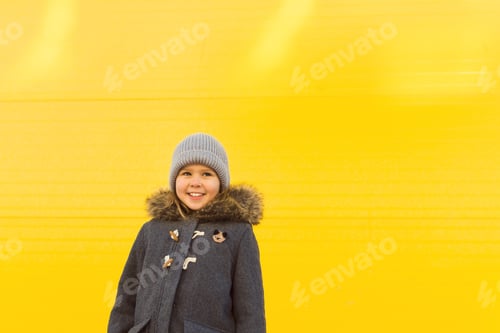 Preview: Happy girl grey coat yellow background