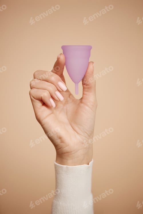 Preview: Hand Holding Menstrual Cup on Beige