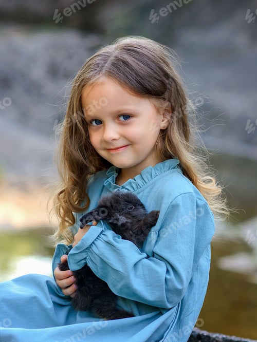 Preview: little girl near the stream with a rabbit in the summer in nature