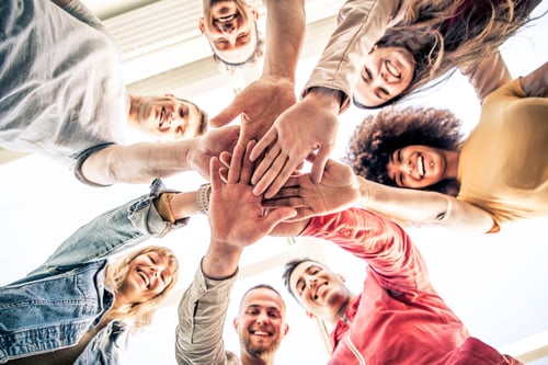 Preview: Young happy people stacking hands together outcoor