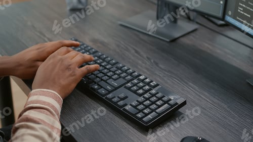 Preview: Closeup of african american programer hands typing code on keyboard while looking at computer