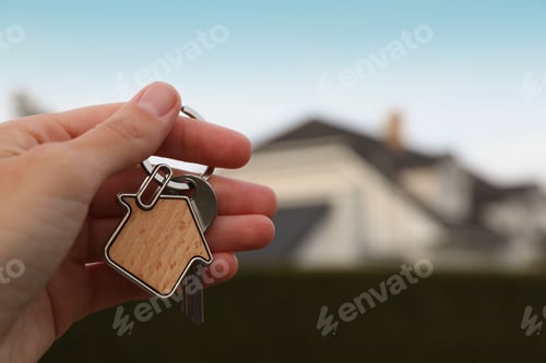 Preview: Woman holding house keys outdoors, closeup with space for text. Real estate agent