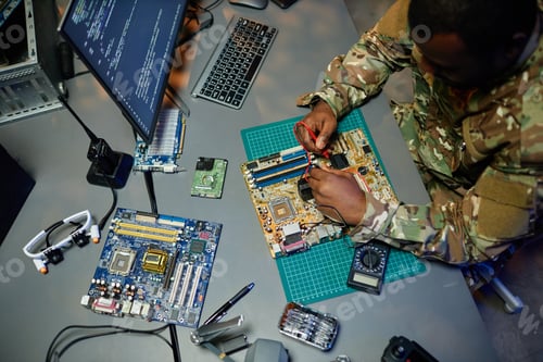 Preview: Above angle of young man in military uniform repairing motherboard