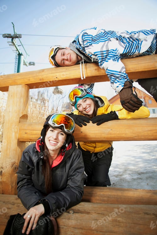 Preview: Three friends wearing skiwear on wooden fence