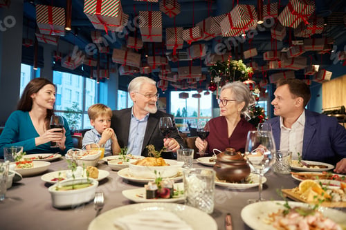 Preview: Happy family enjoying Christmas dinner together and toasting